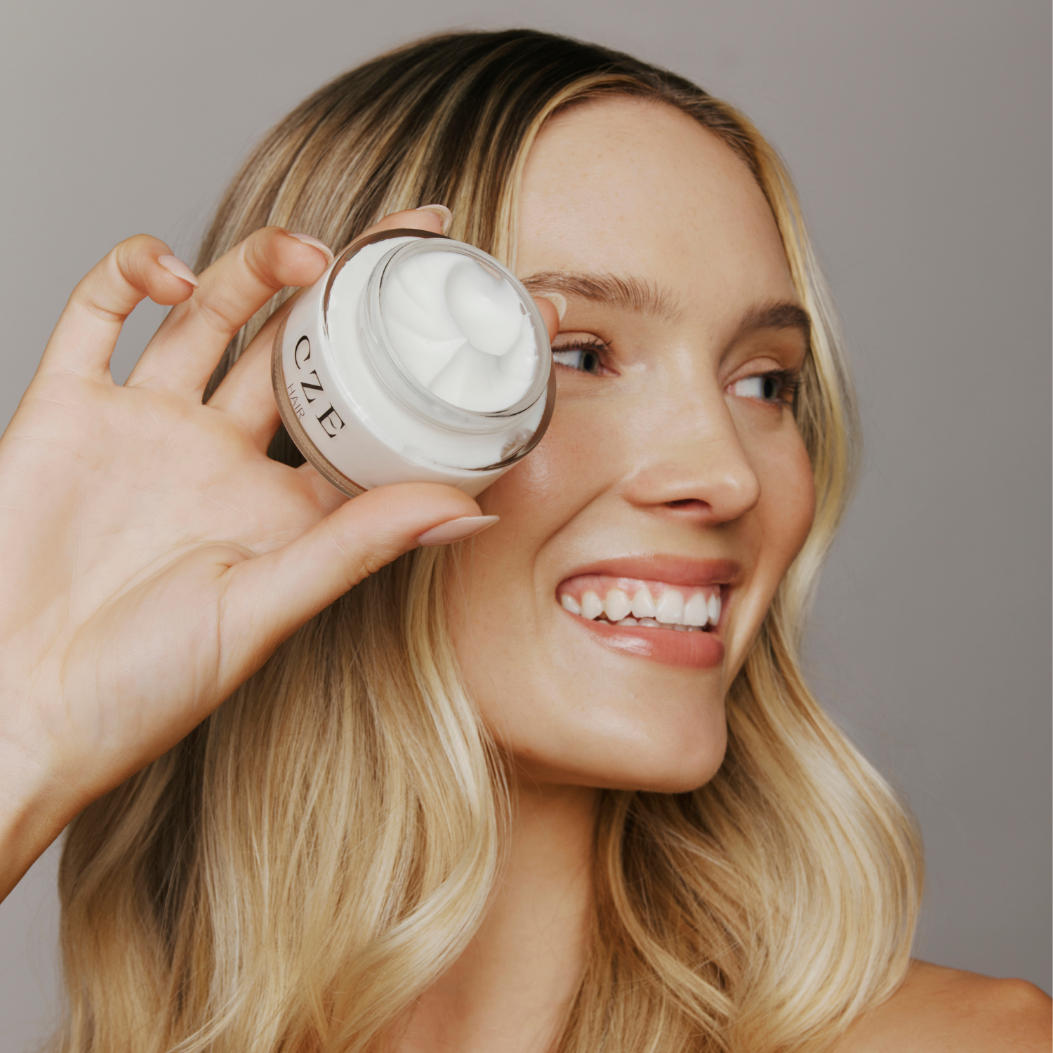 Model holding CZE Hair curl defining cream – lightweight and anti-frizz styling solution.